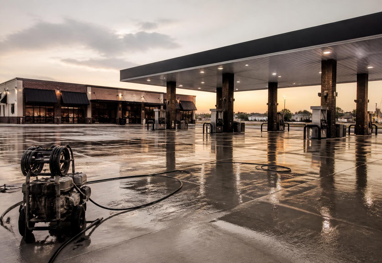 Commercial service station forecourt being pressure washed at dawn